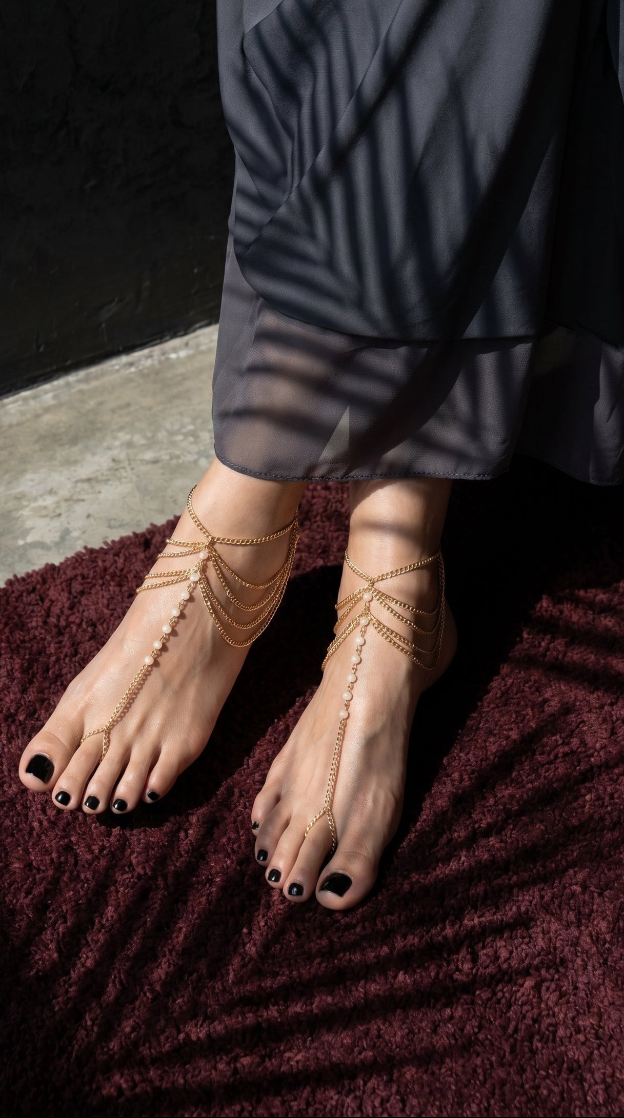 Feet with gold anklets on a dark background